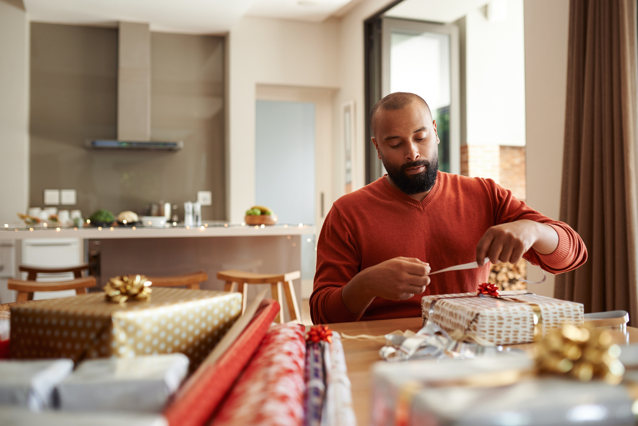 A man wrapping holiday presents at home